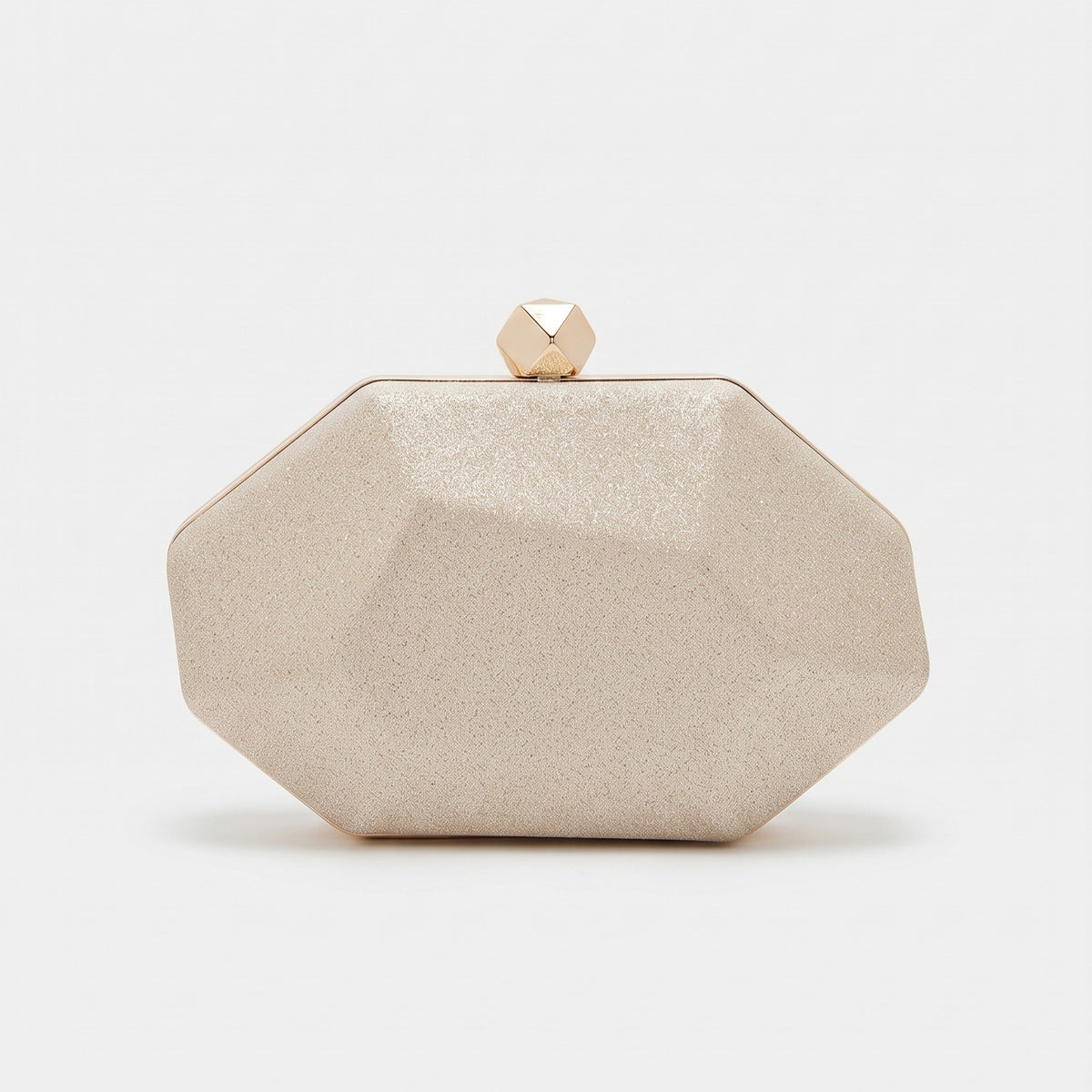 A faceted octagonal clutch bag in a textured champagne beige finish with a small gold geometric clasp on top, set against a plain white background.