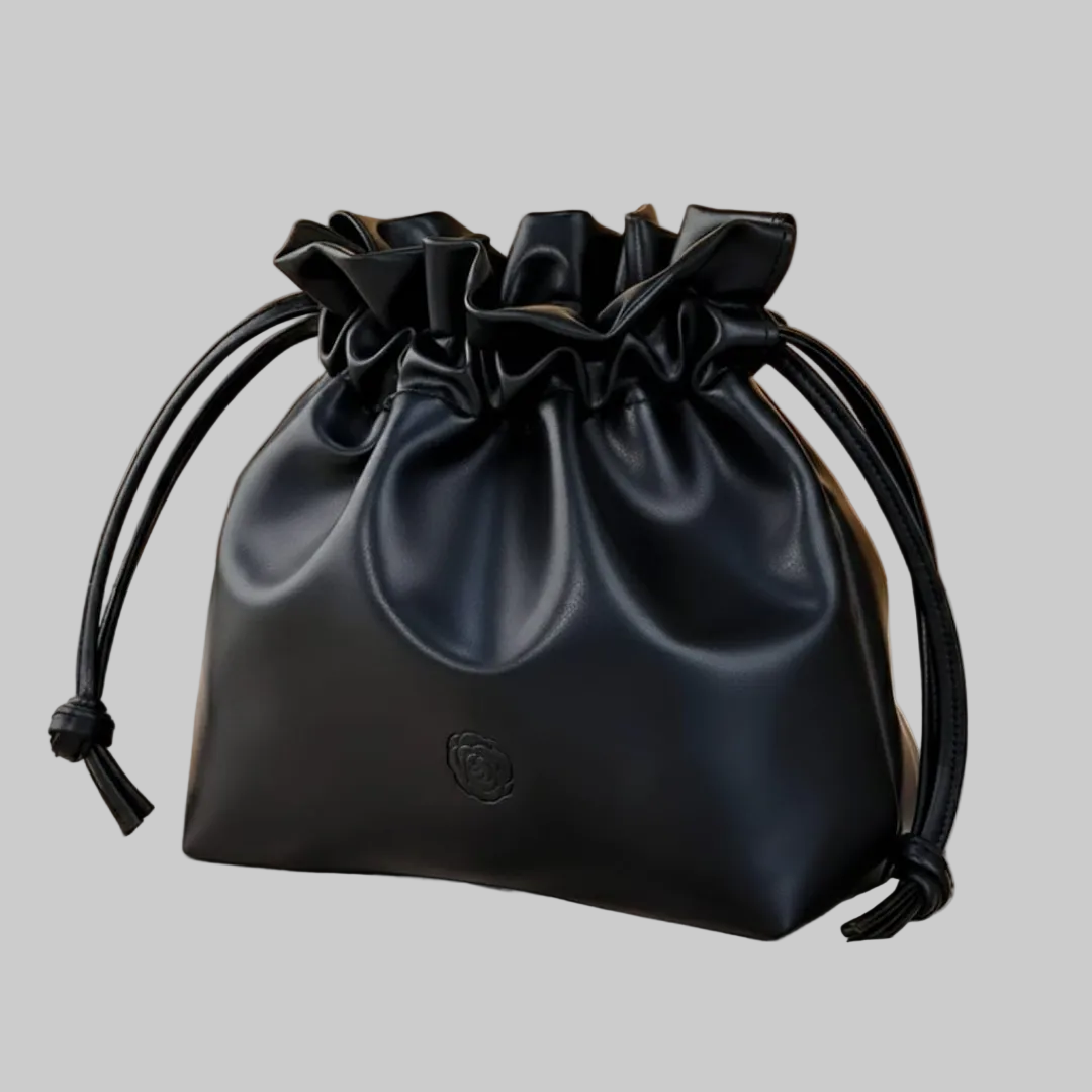 Black drawstring bag on a beige surface with a brown background