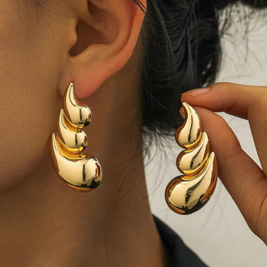Gold earrings being worn and held up to the ear