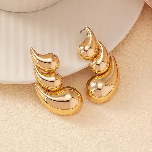 Gold earrings on a beige background