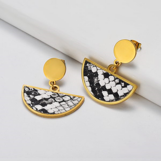 Gold and black patterned earrings on a white surface