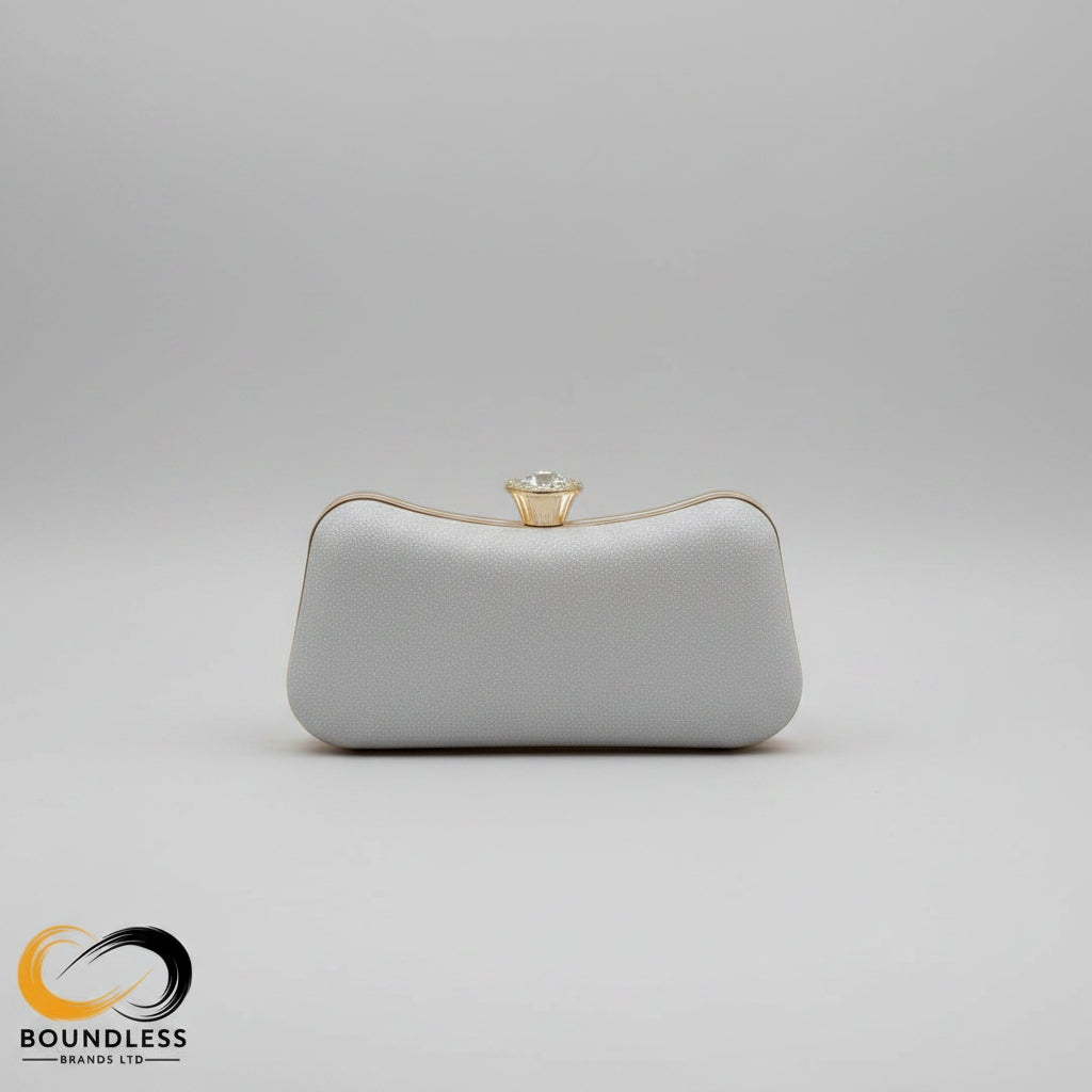 Silver clutch with a decorative clasp on a wooden table with books and glasses.