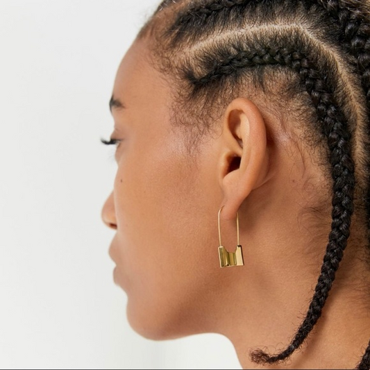 Profile of a person with braided hair wearing a gold earring on a white background
