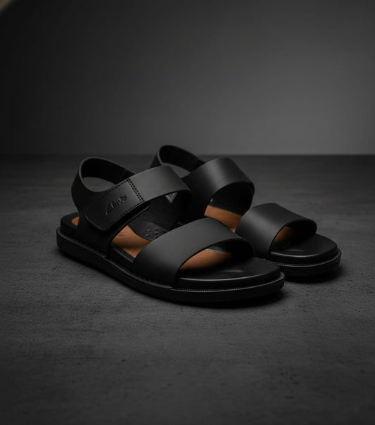 Black sandals on a dark gray surface with a dark background