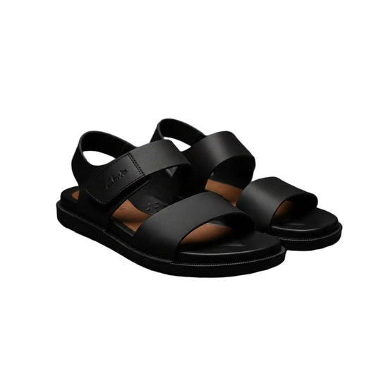 Black sandals on a dark gray surface with a dark background