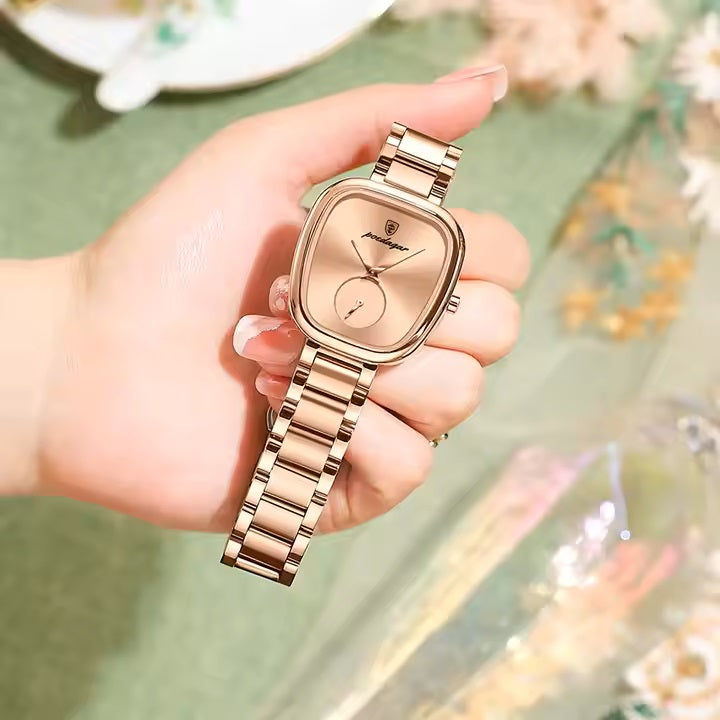 Rose gold watch held in a hand with a blurred background