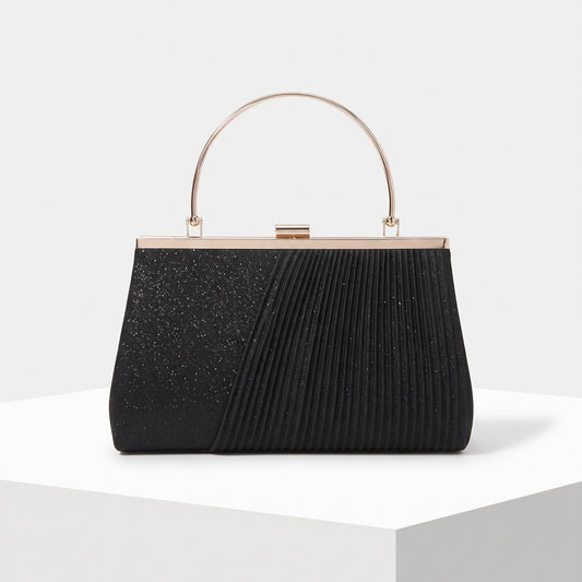 A black evening clutch bag with a split design, featuring a glittery textured left half and a pleated right half, with a gold-tone metal frame and top handle, displayed on a white pedestal.