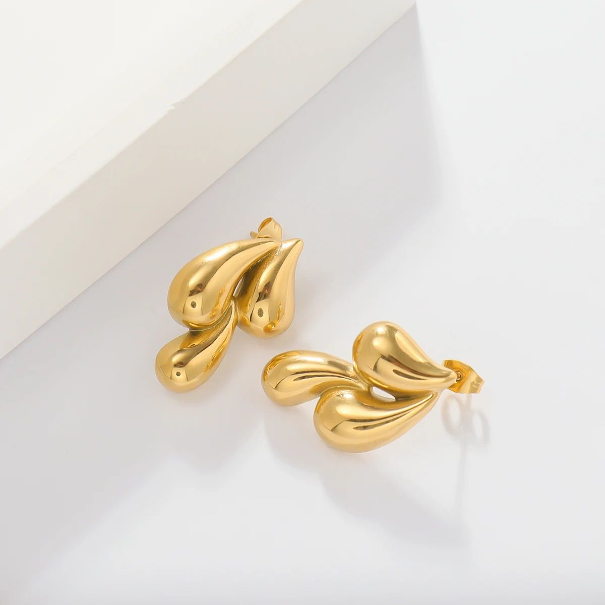 Pair of gold earrings on a light gray background
