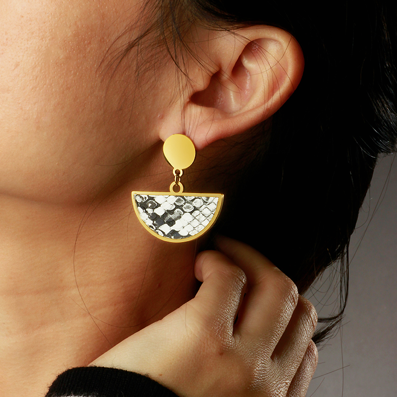 Close-up of a person wearing a gold and black patterned earring.