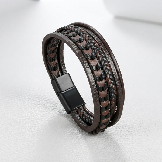 A multi-strand brown leather bracelet with braided details and a black magnetic clasp, displayed on a light gray textured surface.