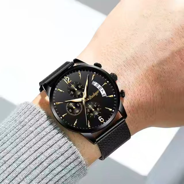 Black wristwatch with detailed face on a wrist, wearing a gray sweater.