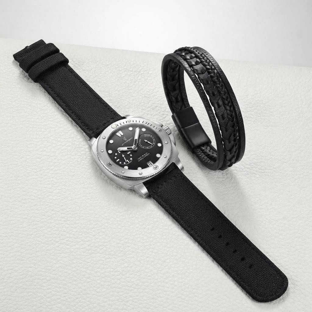 A silver-tone wristwatch with a black dial and black fabric strap, shown alongside a black braided bracelet on a light textured surface.