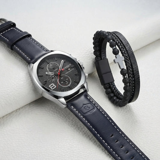 A men's watch with a dark blue leather strap and silver-toned case, displayed alongside a black beaded bracelet with a silver cross clasp on a light textured background.